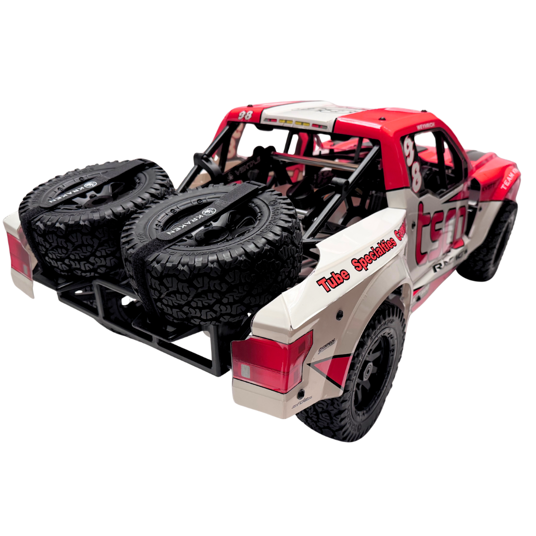 Red and beige off-road model truck with large black tires on a white background