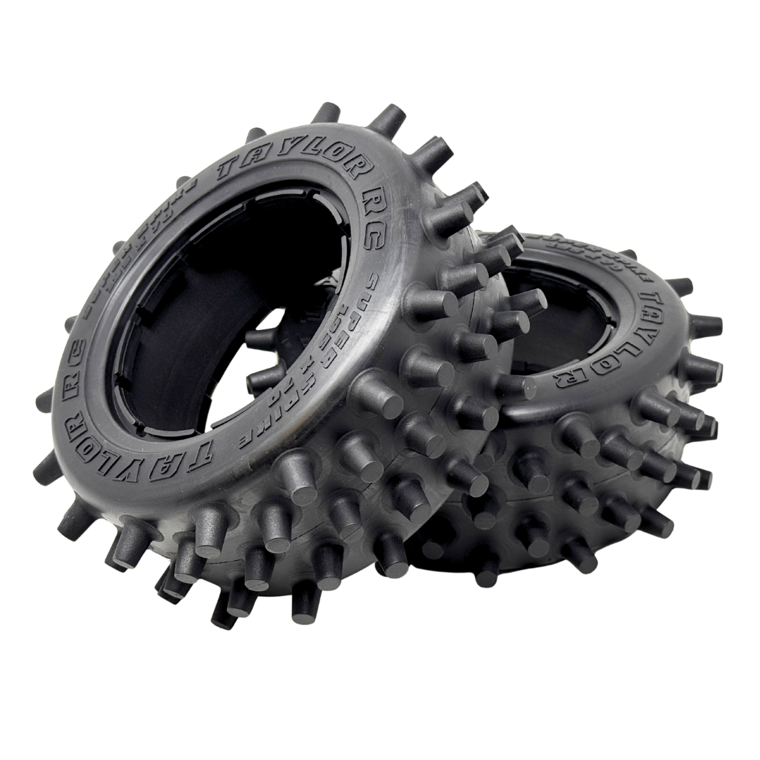 Two black off-road tires with spiky tread pattern on a white background